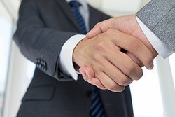 Two people in suits shaking hands.
