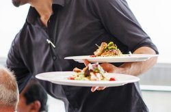 A server holds two plates of modernist food.
