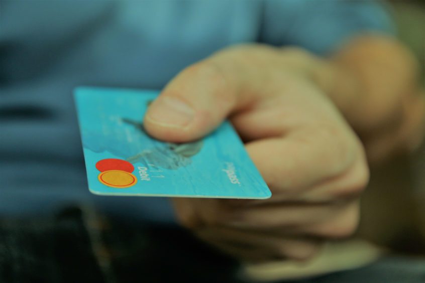 A person holding out a debit card.