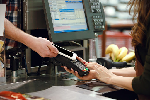 A cashier scanning a smartphone for purchase.